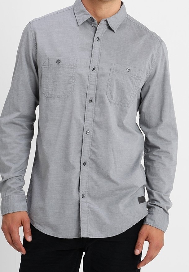 Chemise grise à boutons avec col, deux poches poitrine et ourlet droit. En tissu tissé à texture lisse.