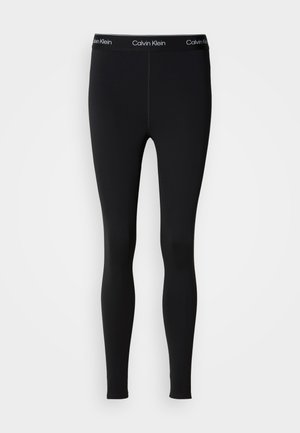 Melni legingi, kas izgatavoti no elastīga auduma, ar pieguļošu dizainu un kontrastējošu baltu Calvin Klein logo uz jostas.