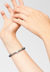 Bracciale con perline che presenta perline grigie, blu e argentate con un accento metallico rotondo. Design elastico che si adatta comodamente al polso.