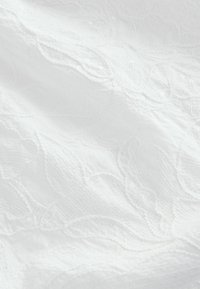 Tissu blanc présentant un design brodé floral complexe avec des coutures texturées et de subtiles accents de perles. Matériau doux et léger.