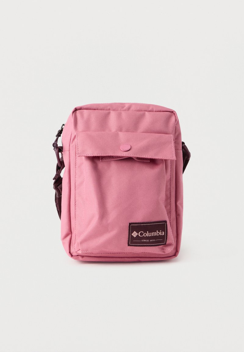Ροζ τσαντάκι ώμου από ύφασμα με εμπρός καπάκι, κούμπωμα με πάτημα και ρυθμιζόμενο λουρί· ετικέτα με το λογότυπο Columbia στο κάτω μέρος.