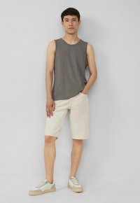 Grijze mouwloze tanktop, off-white shorts en beige sneakers met grijze accenten. Eenvoudig ontwerp en casual pasvorm, geschikt voor warm weer.