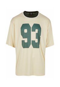 Cremefarvet t-shirt med korte ærmer, der har et stort grønt "93" grafik på forsiden. Rund hals med kontrastkant.