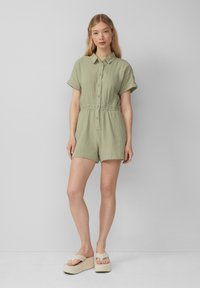 Romper corto a maniche corte verde chiaro con colletto, bottoni frontali e vita elastica. Tessuto morbido e vestibilità comoda.