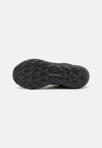 Semelle de chaussure en caoutchouc noir avec un motif de crantage texturé, présentant un logo central. Design adapté pour une traction et une durabilité en extérieur.
