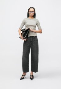 Šedý přiléhavý top, černé džíny s širokými nohavicemi, černá kabelka do ruky a černé špičaté pantofle na podpatku s dekorativními kovovými prvky. Dlouhý zapletený účes a brýle.