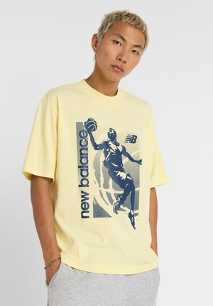 Geel katoenen T-shirt met een marineblauw ontwerp van een speler die een basketbal schiet. Crewneck, korte mouwen, relaxte pasvorm.