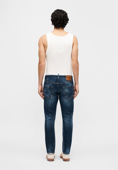 Σκούρα μπλε στενά τζιν με ελαφρύ ξεθώριασμα, φορε μένα με λευκό αμάνικο τοπ. Διαθέτουν καφέ δερμάτινο ταμπελάκι στη πίσω μέση.