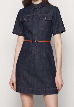 Ciemnoniebieska sukienka dżinsowa z krótkim rękawem, z kieszeniami na piersi z przodu, kołnierzem oraz cienkim brązowym paskiem w talii, na stojącej osobie.