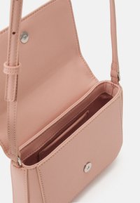 Różowa prostokątna torba na ramię wykonana z teksturowanego materiału syntetycznego, z magnetycznym zatrzaskiem, regulowanym paskiem i wieloma wnętrznymi przegródkami.