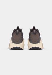 Καφέ και κρέμα αθλητικά παπούτσια με υφή στην επάνω επιφάνεια, μαλακό κολάρο στη φτέρνα και μαύρη καουτσούκ σόλα. Έχει τράβηγμα στο πίσω μέρος για εύκολη εφαρμογή.