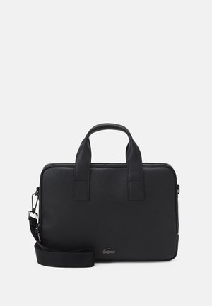 Mallette en cuir noir texturé avec doubles poignées, bandoulière détachable et un petit logo alligator en bas à droite à l’avant.