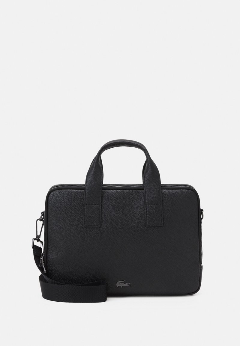 Mallette en cuir noir texturé avec doubles poignées, bandoulière détachable et un petit logo alligator en bas à droite à l’avant.