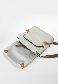 Messenger bag grigio chiaro con accenti in pelle marrone; presenta una tasca frontale con zip e un ampio interno foderato con un motivo a griglia.