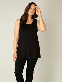 Zwarte mouwloze tuniek met een ronde hals, zijsplitten en een losse pasvorm, gecombineerd met strakke zwarte broeken. Gladde stofstructuur.