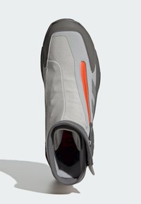 Grey and orange athletic shoe with a zip closure, textured synthetic upper, and a padded interior. Features a rounded toe and high ankle design.