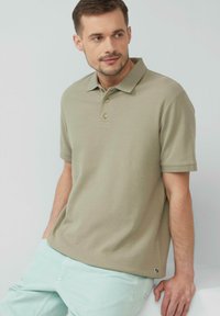 Khaki polo-shirt met een klassieke kraag, drie knopen en korte mouwen; gladde, gestructureerde stof; logotag aan de zoom.