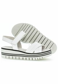 Sandalias de plataforma blancas con correa ajustable, que presentan una suela texturizada, rayas horizontales en blanco y negro, y un diseño en cruce en la parte delantera.