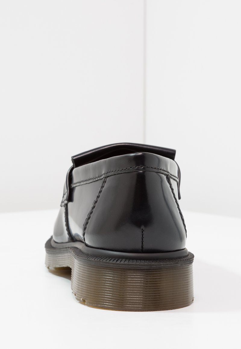 Scarpa in vernice nera con punta arrotondata, tacco basso e suola testurizzata a contrasto. Presenta dettagli cuciti e un design elegante.
