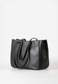 Zwarte leren schoudertas met een gestructureerde afwerking, dubbele handvatten bovenaan en een open ontwerp. Eenvoudig en functioneel met een ruime binnenkant.