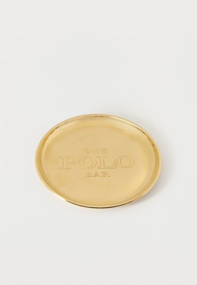 Στρογγυλός χρυσός δίσκος με χαραγμένο κείμενο "THE POLO BAR" στο κέντρο σε απλό λευκό φόντο.