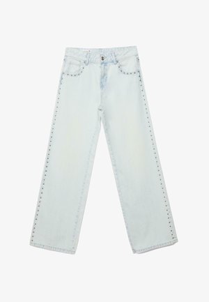 Jean en denim bleu clair à jambes larges avec des clous métalliques le long des coutures extérieures, fermeture frontale par bouton et zip, et design à cinq poches.