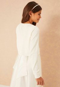 Fehér, rövidített pulóver, puha kötött anyagból, hosszú ujjakkal és bordázott nyakkivágással. Hátsó részén megkötős masni díszíti a réteges ruhát.