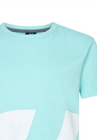 Světle modré bavlněné tričko s kulatým výstřihem, které má na přední straně velký bílý grafický design a krátké rukávy.