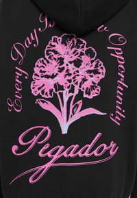 Hoodie noir avec un motif floral rose et le texte : « Chaque jour est une nouvelle opportunité » et « Pigador », avec une police de caractères élégante.