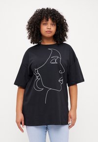 Svart T-skjorte med en hvit linjetegning av et kvinnelig ansikt, rund hals, og korte ermer, kombinert med lyseblå denimjeans.