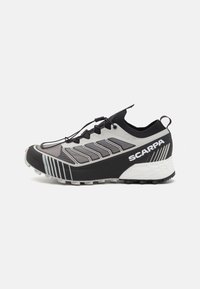 Scarpa da corsa nera e grigia con tomaia texturizzata, sistema di allacciatura unico e suola pronunciata. Presenta un marchio e accenti di design angolari.