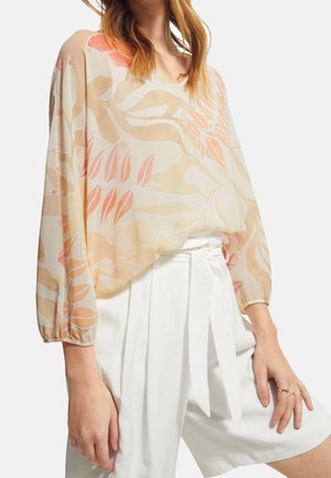 Sheer blouse with a V-neck, featuring floral patterns in soft peach and cream tones. Long sleeves with elastic cuffs, paired with white shorts.