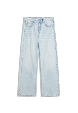 Jean large bleu clair en denim, avec une fermeture à boutons et des clous décoratifs le long des coutures latérales.