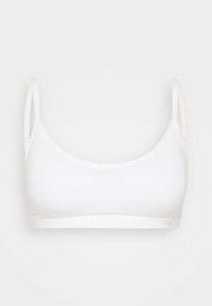 Witte sportbeha van glad, rekbaar materiaal. Beschikt over dunne verstelbare bandjes en een naadloos ontwerp, met een zachte elastische band aan de onderkant.
