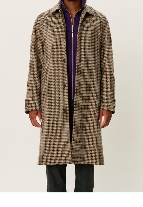 Brun rutmönstrad kappa med krage, med stora knappar och en lös passform. Bärs över en lila zip-up jacka.
