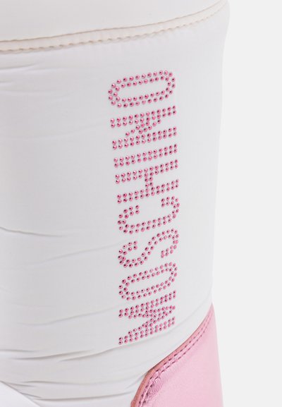 Witte schoen met roze accenten, voorzien van strass-details die een naam verticaal op de zijkant spellen. Glad textuur en atletisch ontwerp.