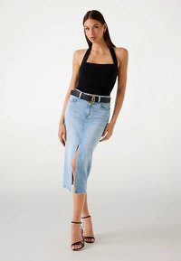 Mustast halterkaelusega top, mis on kombineeritud helesinise teksamidi-seelikuga, millel on ees lõhik, kantud musta vöö ja rihmikontsadega.