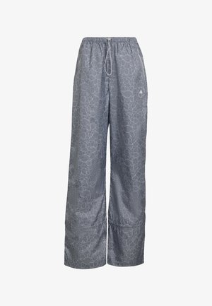 Pantalones gris de pierna ancha con patrón de encaje floral blanco, cintura elástica, cordón ajustable y pequeño logo de Adidas en el muslo derecho.