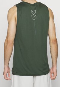 Ciemnozielony sportowy top na ramiączkach z okrągłym dekoltem i bez rękawów, z odblaskowymi białymi strzałkami i tekstem na plecach. Gładka tekstura.