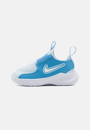 Ténis Nike azuis com um cabedal sintético suave, pormenores em malha, faixa elástica e uma sola branca em borracha. Apresenta um logótipo proeminente na lateral.