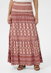 Maxi rok in rode en crèmekleurige patronen. Heeft een smock tailleband en een gelaagd ontwerp met tribale motieven en geometrische vormen.