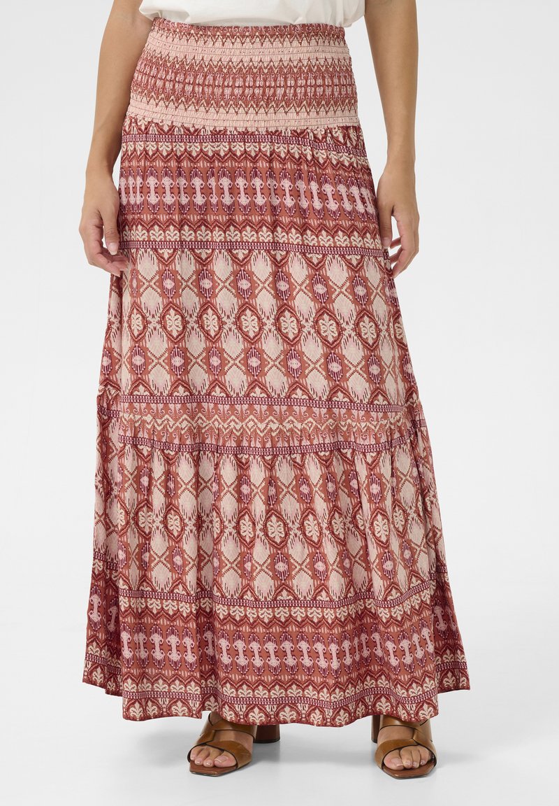 Maxi rok in rode en crèmekleurige patronen. Heeft een smock tailleband en een gelaagd ontwerp met tribale motieven en geometrische vormen.