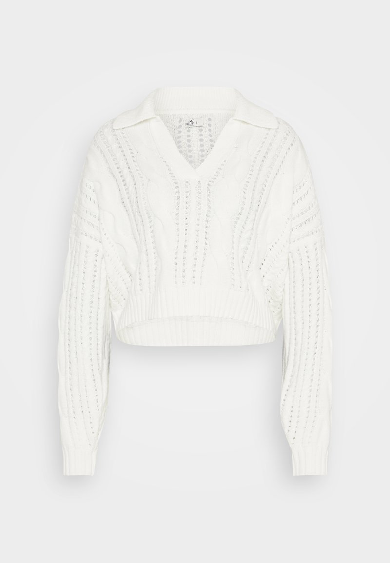 Maglione bianco cropped con scollo a V, design a trecce, polsini e colletto a costine. Motivo testurizzato con sezioni a maglia aperta.