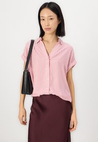 Rosa- und weiß gestreiftes Kurzarmhemd mit Kragen und Knopfleiste, kombiniert mit einem bordeauxfarbenen Satinrock und einer schwarzen Ledertasche.
