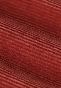 Tissu en textile avec un design texturé et côtelé, dans différentes nuances de brun-rouge. Surface douce avec des lignes parallèles visibles et une profondeur subtile.