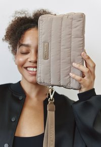 Beige handtas met quilten, een gladde textuur, gouden hardware en een afneembare schouderband. Heeft het merknametag in zilver aan de zijkant.