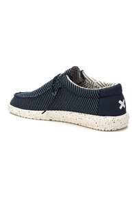 Zapato de lona a rayas azul y blanco con punta redondeada, detalle de cordones y suela blanca moteada. Presenta un acento de logotipo en el talón.