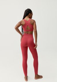 Röd träningstights-set med en racerback sportbh med utskärning och höga leggings med texturerade detaljer. Slätt, figurnära material.