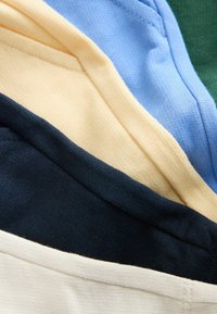 Vrstvy bavlněné látky v zelené, modré, béžové, námořnické a krémové barvě. Texturovaný, měkký povrch s viditelným prošíváním na každé vrstvě.