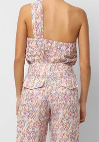 Mønstret one-shoulder jumpsuit med multicolorede diamantformer, løst fit og to knap-lukket baglommer. Blødt, struktureret stof.